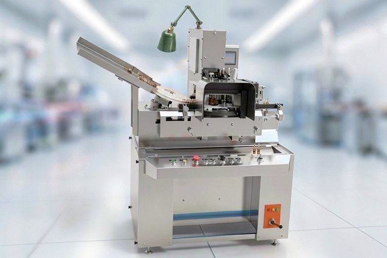 Automated manufacturing machine in a bright lab with a conveyor belt and control panel.