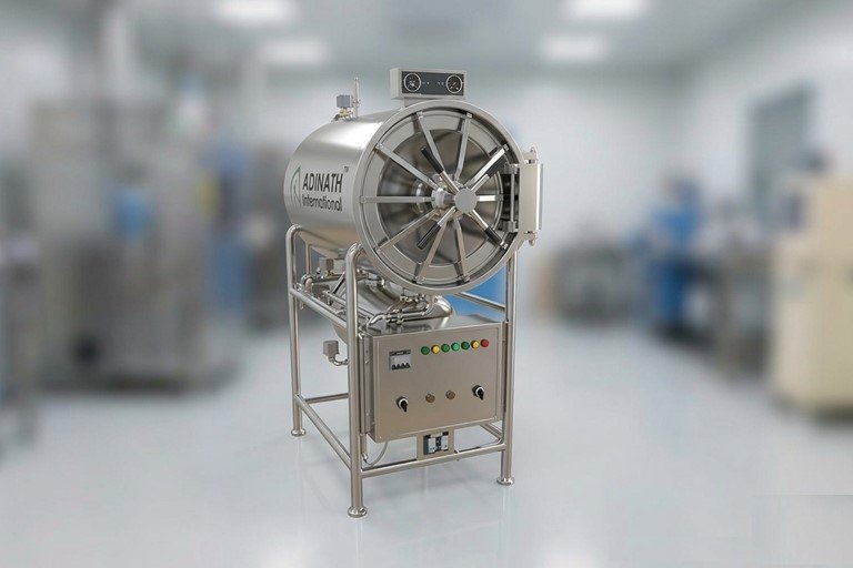 Industrial autoclave machine in a clean laboratory, stainless steel with a large circular door and a control panel on a stand.