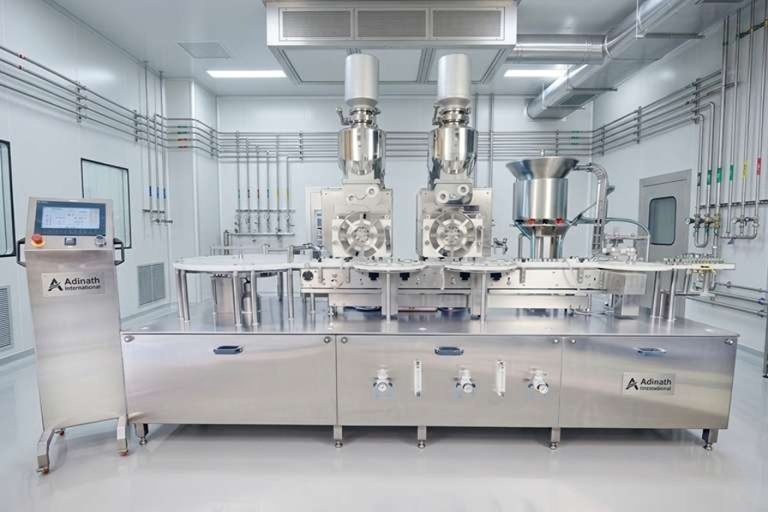 Industrial stainless-steel filling and capping line in a cleanroom, with control panel on the left.