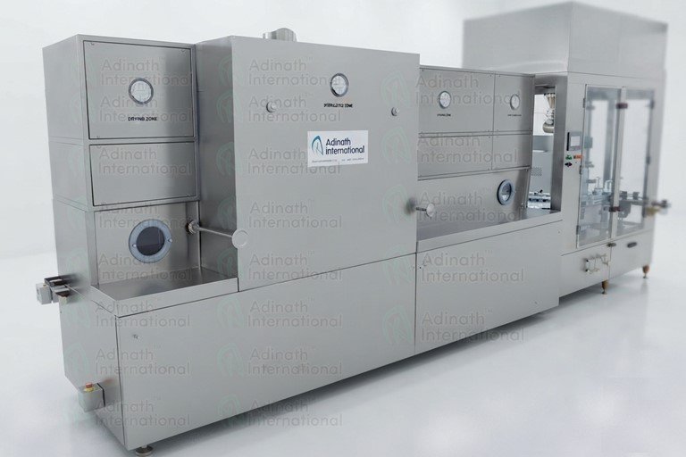 Large stainless steel industrial processing machine in a clean laboratory setting, with control panels and safety doors, labeled Adinath International.